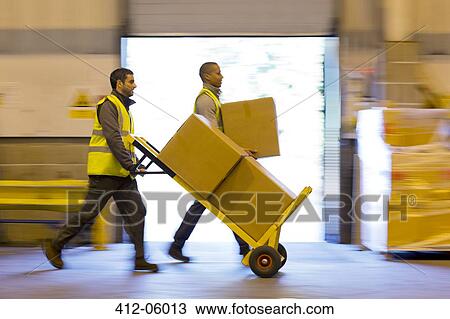 Workers carting boxes in warehouse View Large Photo Image Stock Image - Workers carting boxes in warehouse. Fotosearch