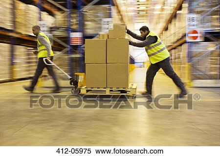 Workers carting boxes in warehouse View Large Photo Image Stock Photography - Workers carting boxes in warehouse. Fotosearch