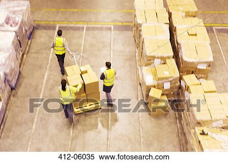 Workers carting boxes in warehouse View Large Photo Image Stock Photography - Workers carting boxes in warehouse. Fotosearch