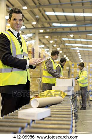 Workers checking packages on conveyor belt in warehouse View Large Photo Image Stock Photograph - Workers checking packages on conveyor belt in warehouse. Fotosearch