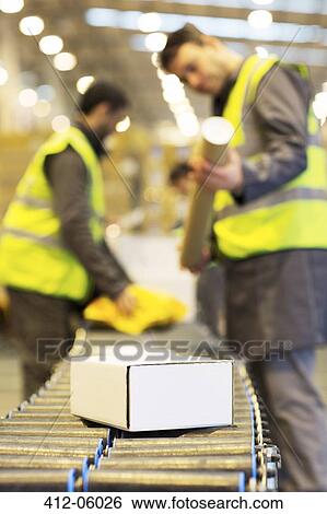 Workers checking packages on conveyor belt in warehouse View Large Photo Image Stock Photograph - Workers checking packages on conveyor belt in warehouse. Fotosearch