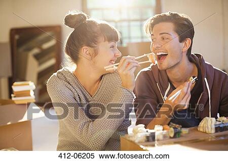 Stock Photography - Couple eating sushi together in new home. Fotosearch