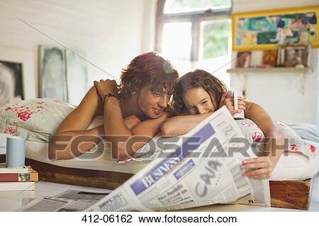 Couple reading newspaper together in bed View Large Photo Image Stock Image - Couple reading newspaper together in bed. Fotosearch