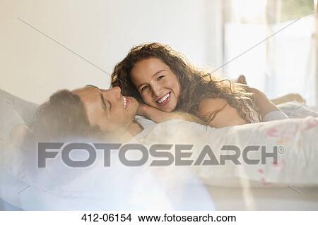 Couple relaxing together in bed View Large Photo Image Picture - Couple relaxing together in bed. Fotosearch