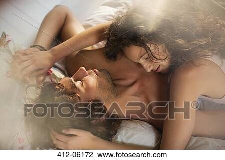 Stock Image - Couple relaxing together in bed. Fotosearch