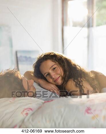 Couple relaxing together in bed View Large Photo Image Stock Photo - Couple relaxing together in bed. Fotosearch