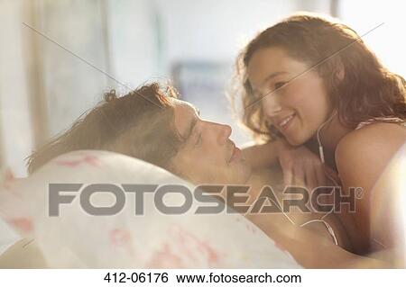 Couple relaxing together in bed View Large Photo Image Stock Photograph - Couple relaxing together in bed. Fotosearch