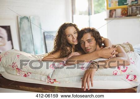 Couple relaxing together on bed View Large Photo Image Stock Photo - Couple relaxing together on bed. Fotosearch