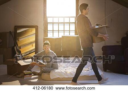 Stock Image - Couple unpacking boxes in attic. Fotosearch