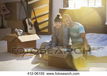 Stock Image - Couple unpacking boxes in attic. Fotosearch