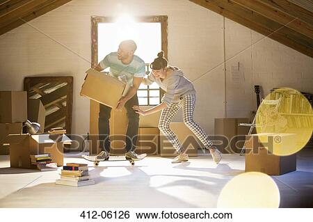 Stock Photograph - Couple unpacking boxes in attic. Fotosearch