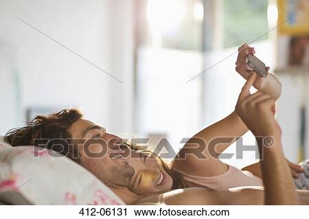 Couple using cell phone in bed View Large Photo Image Stock Image - Couple using cell phone in bed. Fotosearch