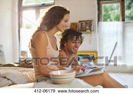 Stock Photo - Couple using laptop together in bed. Fotosearch