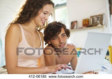Couple using laptop together in bed View Large Photo Image Stock Photography - Couple using laptop together in bed. Fotosearch