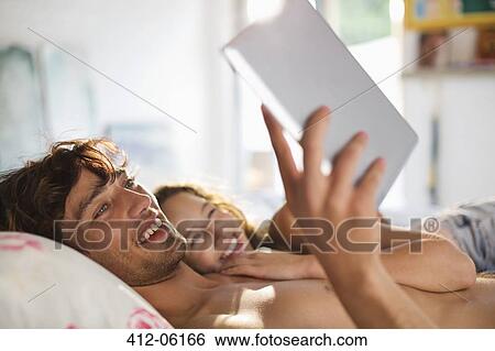 Couple using tablet computer in bed View Large Photo Image Stock Photograph - Couple using tablet computer in bed. Fotosearch