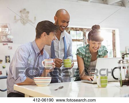 Stock Image - Friends using laptop together at breakfast. Fotosearch