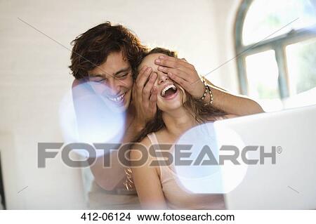 Man covering girlfriend's eyes indoors View Large Photo Image Picture - Man covering girlfriend's eyes indoors. Fotosearch