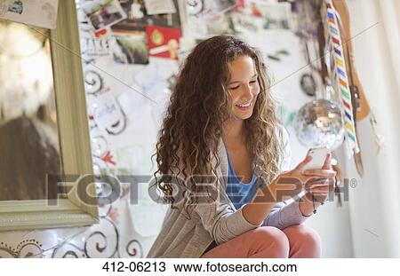 Woman using cell phone in bedroom View Large Photo Image Stock Image - Woman using cell phone in bedroom. Fotosearch