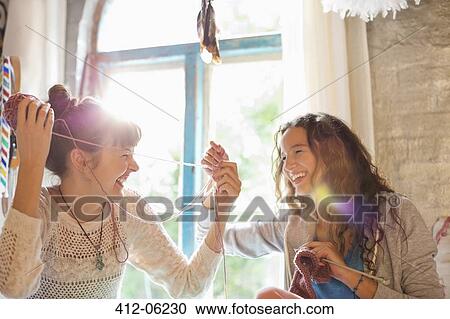 Stock Image - Women playing with yarn together. Fotosearch