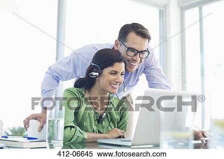 Business people using laptop together at desk View Large Photo Image Stock Photography - Business people using laptop together at desk. Fotosearch