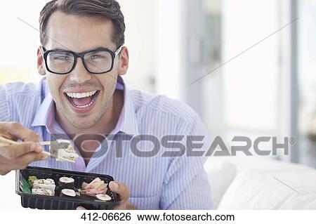 Businessman eating sushi in office View Large Photo Image Stock Photograph - Businessman eating sushi in office. Fotosearch