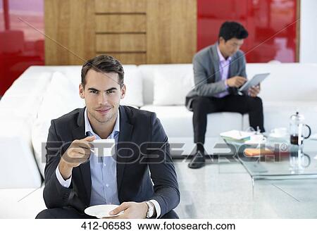 Businessman having cup of coffee in office View Large Photo Image Stock Image - Businessman having cup of coffee in office. Fotosearch