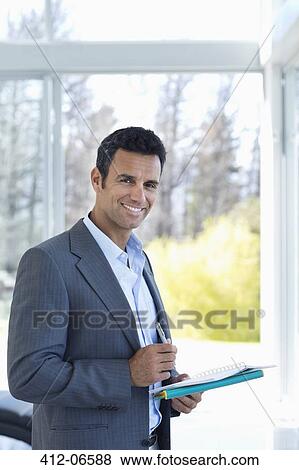 Businessman reading papers in office View Large Photo Image Stock Photo - Businessman reading papers in office. Fotosearch