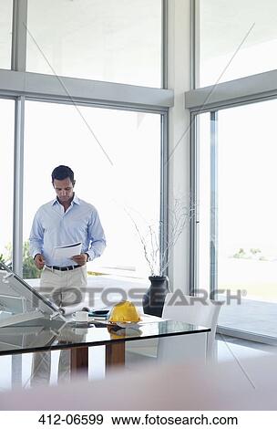 Stock Photo - Businessman reading papers in office. Fotosearch