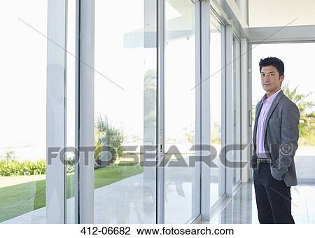 Businessman standing at office window View Large Photo Image Stock Image - Businessman standing at office window. Fotosearch