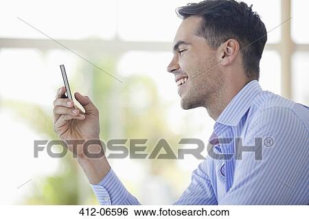 Stock Photograph - Businessman using cell phone in office. Fotosearch