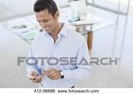 Stock Photograph - Businessman using cell phone in office. Fotosearch