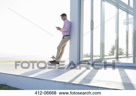 Stock Photo - Businessman using cell phone outside office. Fotosearch