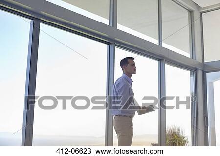 Businessman using tablet computer at window View Large Photo Image Stock Image - Businessman using tablet computer at window. Fotosearch