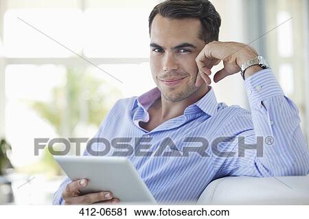 Businessman using tablet computer on sofa View Large Photo Image Stock Image - Businessman using tablet computer on sofa. Fotosearch