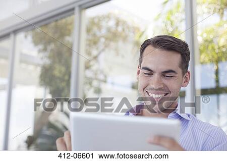 Stock Image - Businessman using tablet computer outdoors. Fotosearch