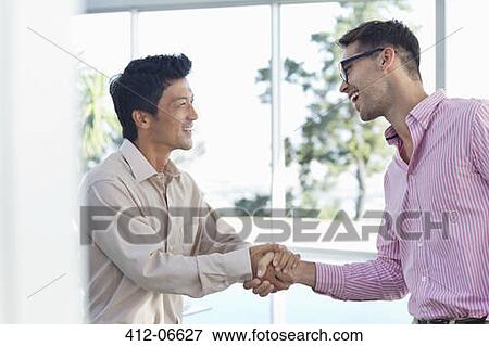 Stock Photo - Businessmen shaking hands in office. Fotosearch