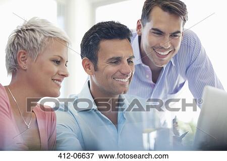 Businesspeople using laptop at desk View Large Photo Image Stock Photo - Businesspeople using laptop at desk. Fotosearch