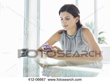 Businesswoman using cell phone at desk View Large Photo Image Stock Photo - Businesswoman using cell phone at desk. Fotosearch