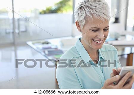 Stock Photograph - Businesswoman using cell phone in office. Fotosearch