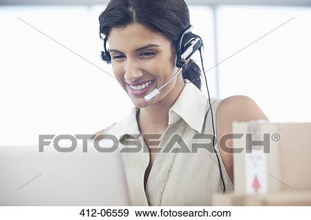 Businesswoman wearing headset at desk View Large Photo Image Stock Photo - Businesswoman wearing headset at desk. Fotosearch
