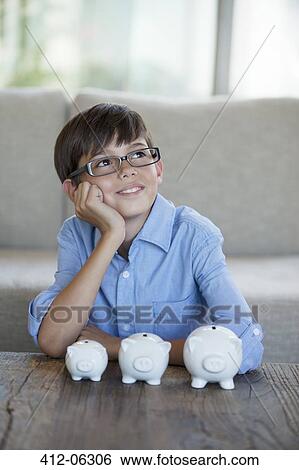 Boy sitting with piggy banks at coffee table View Large Photo Image Stock Photograph - Boy sitting with piggy banks at coffee table. Fotosearch