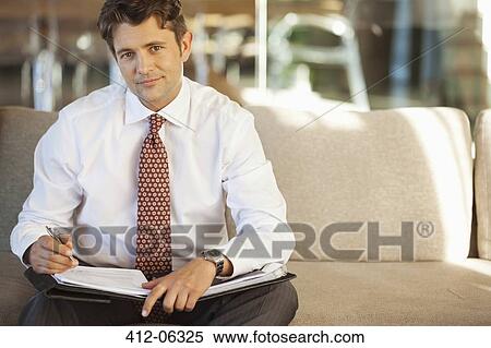 Businessman making notes on sofa View Large Photo Image Stock Photography - Businessman making notes on sofa. Fotosearch