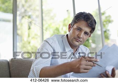 Businessman reading papers on sofa View Large Photo Image Stock Photograph - Businessman reading papers on sofa. Fotosearch