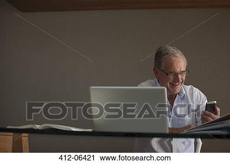 Businessman using cell phone at desk View Large Photo Image Stock Image - Businessman using cell phone at desk. Fotosearch