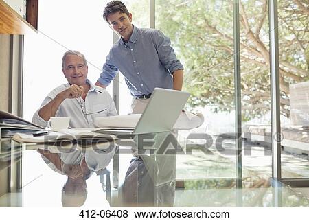 Businessmen smiling at desk View Large Photo Image Stock Photo - Businessmen smiling at desk. Fotosearch