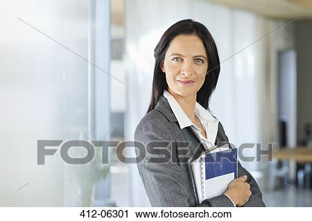 Stock Image - Businesswoman smiling in office. Fotosearch