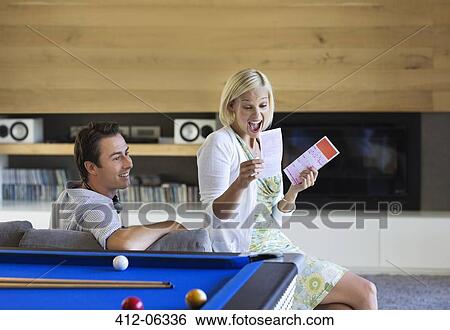 Couple checking lottery tickets on sofa View Large Photo Image Stock Photograph - Couple checking lottery tickets on sofa. Fotosearch