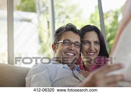 Couple reading newspaper together on sofa View Large Photo Image Stock Image - Couple reading newspaper together on sofa. Fotosearch