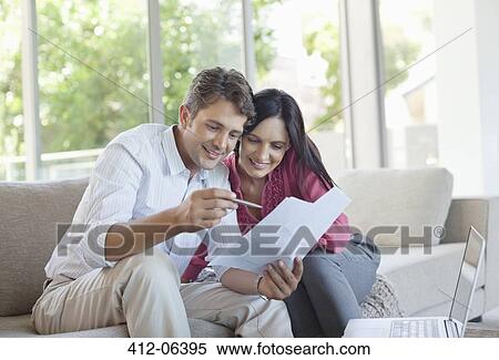Stock Photography - Couple reading papers together on sofa. Fotosearch