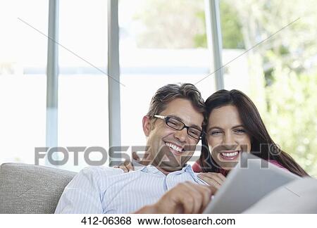 Stock Photo - Couple using tablet computer on sofa. Fotosearch